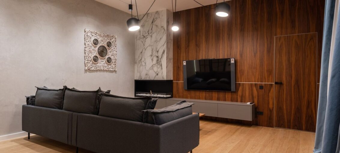 Moderne stue med sofa, tregulv og TV-vegg i tre og marmor